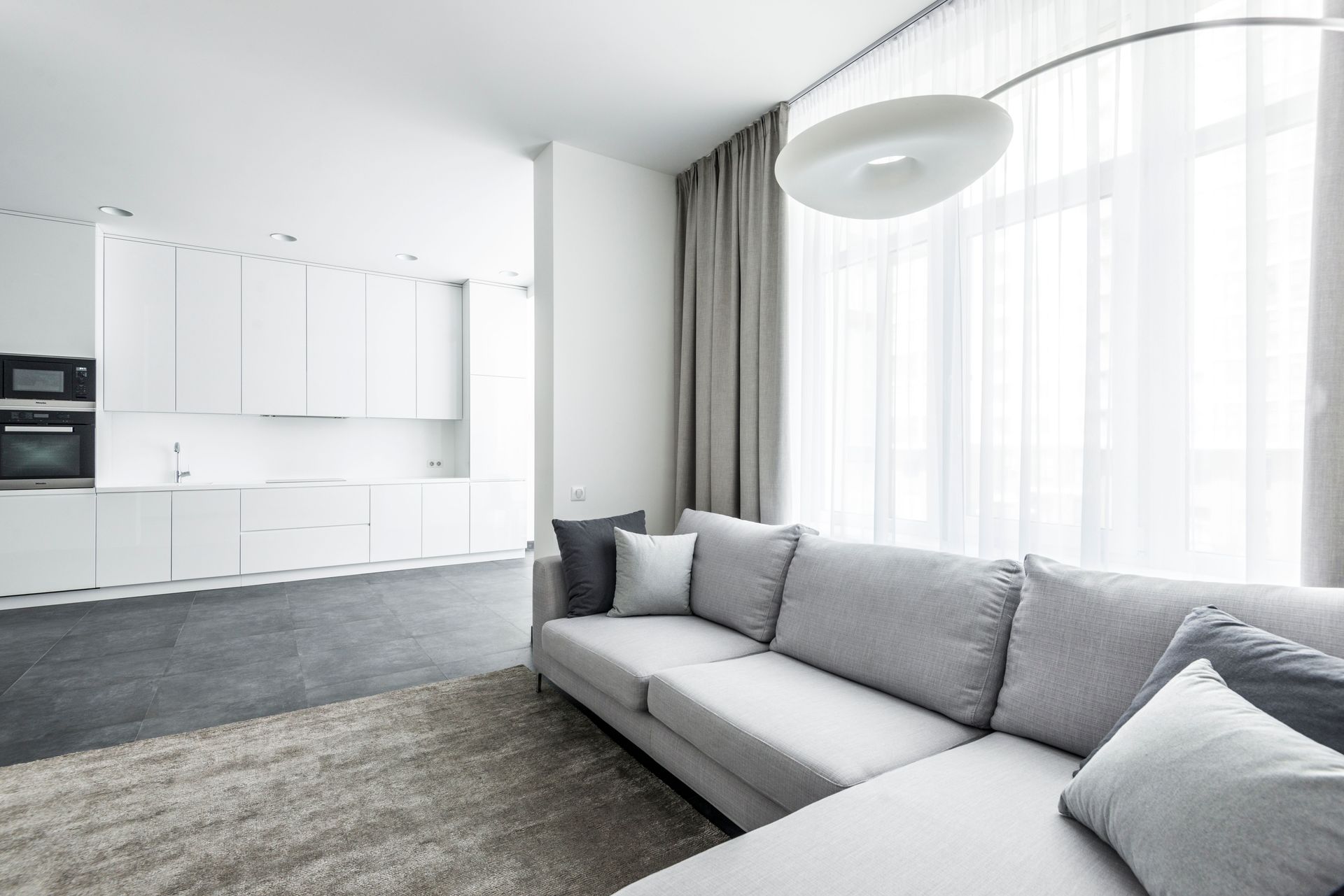 Bright modern living area featuring a cozy sofa and minimalist kitchen background.